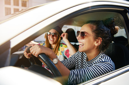 Laughing young girlfriends traveling in a car, a Person Photo by Stefan & Janni