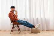 Man having rest at home sitting on chair, drinking coffee, a Photo by Prostock-Studio (Thumbnail 2 of 2)