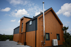 Modern wooden house exterior with metal accents under a blue sky, a Photo by AS photostudio