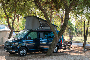 Dark blue camper caravan on camping containing campsite, caravan, and