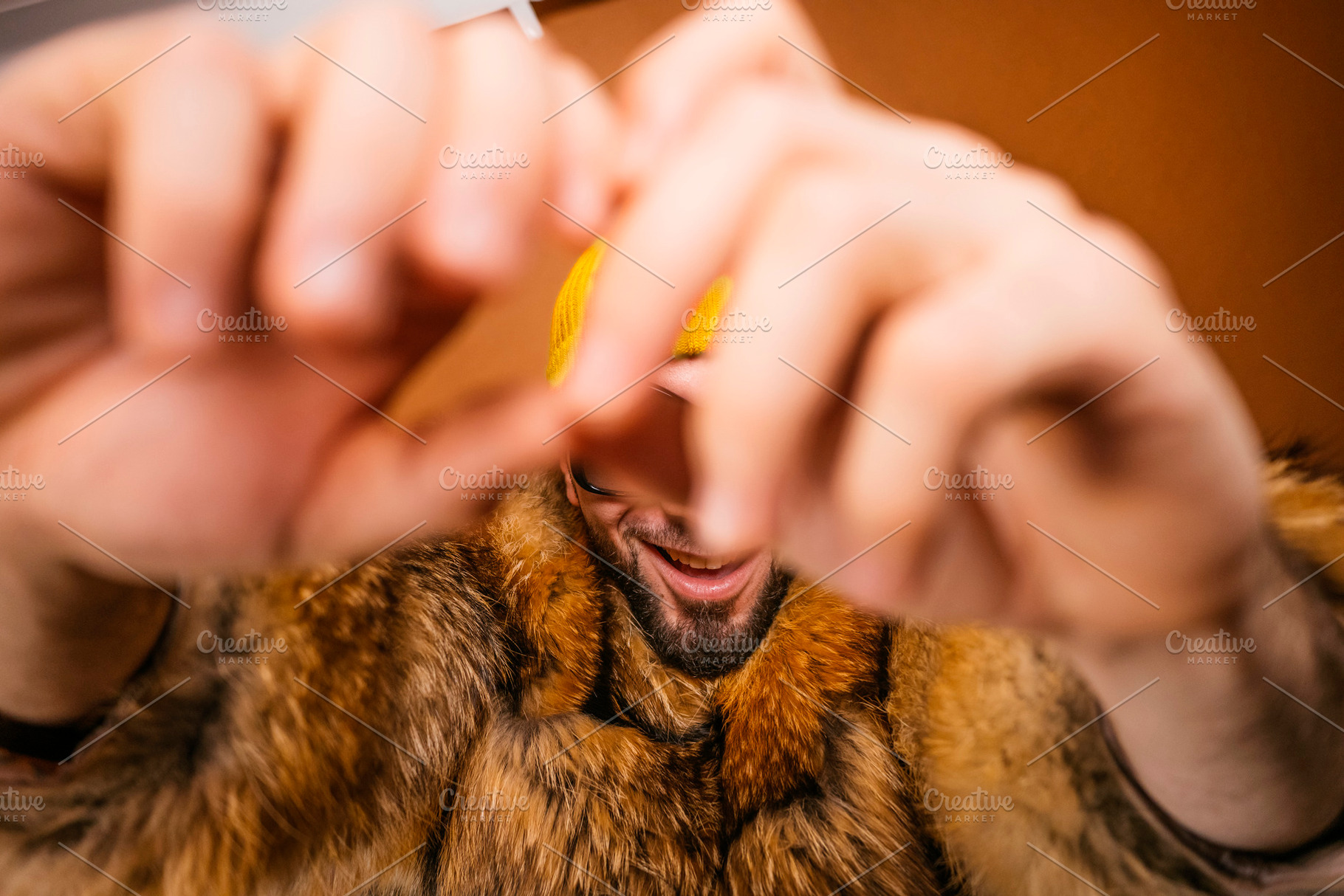 Happy man in fur coat forming heart shape with hands, a Photo by karrastock