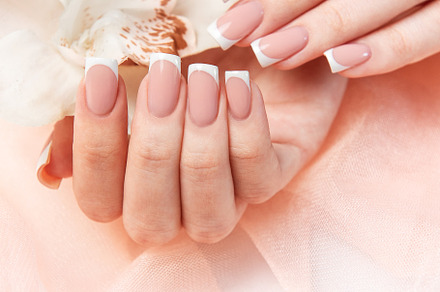 Woman showing french manicure holding white orchid on pink backg
