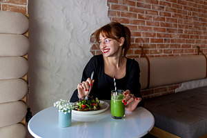 Smiling woman enjoying healthy meal and green smoothie in cafe, a Person Photo by Photostock