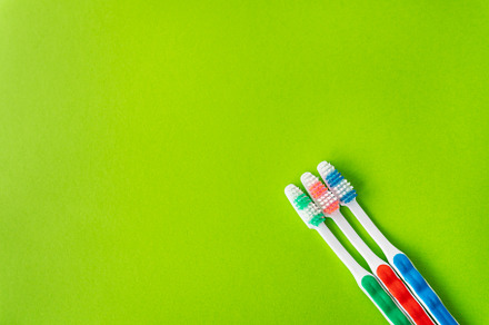 Multi-colored toothbrushes on a green background, the concept of dental care an, a Health & Medical Photo by Artsaba Family