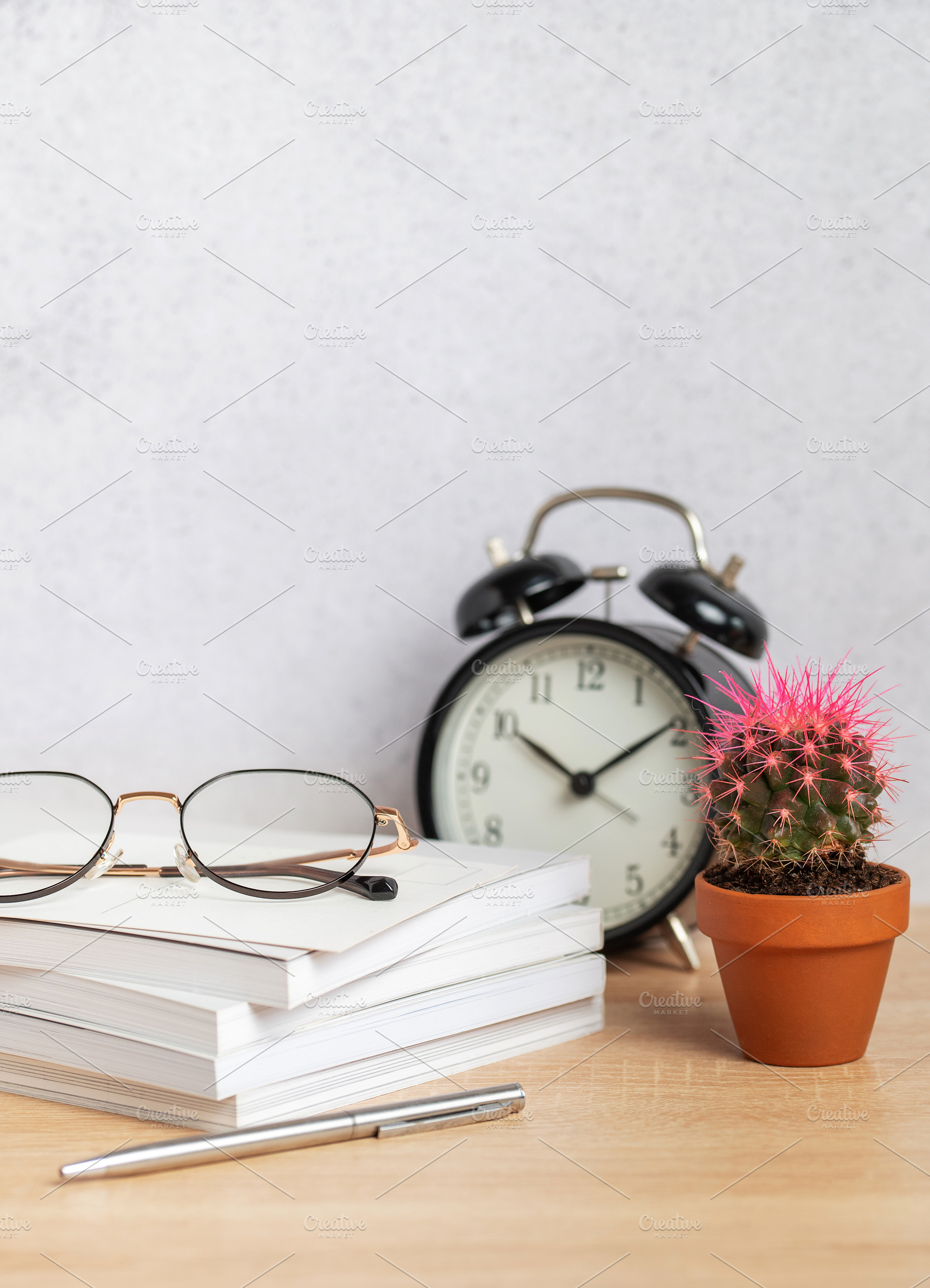 Eyeglasses resting on stack of notebooks with pen, alarm clock,, a Background Photo by Olena Rudo