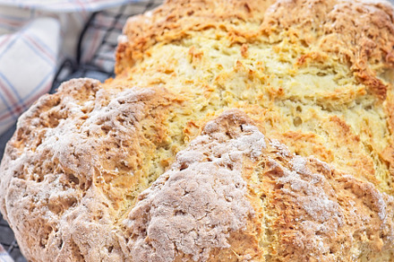 Freshly baked soda bread on cooling rack with butter and honey in the backgroun