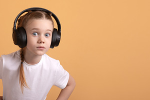 Young girl in white t-shirt wearing large headphones, looking su, a Person Photo by Ales Munt