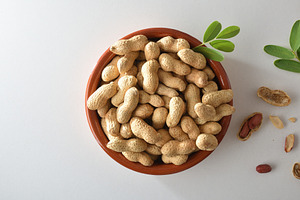 Heap of peanuts in clay bowl with leaves in the center, a Food & Drink Photo by Davizro's Market