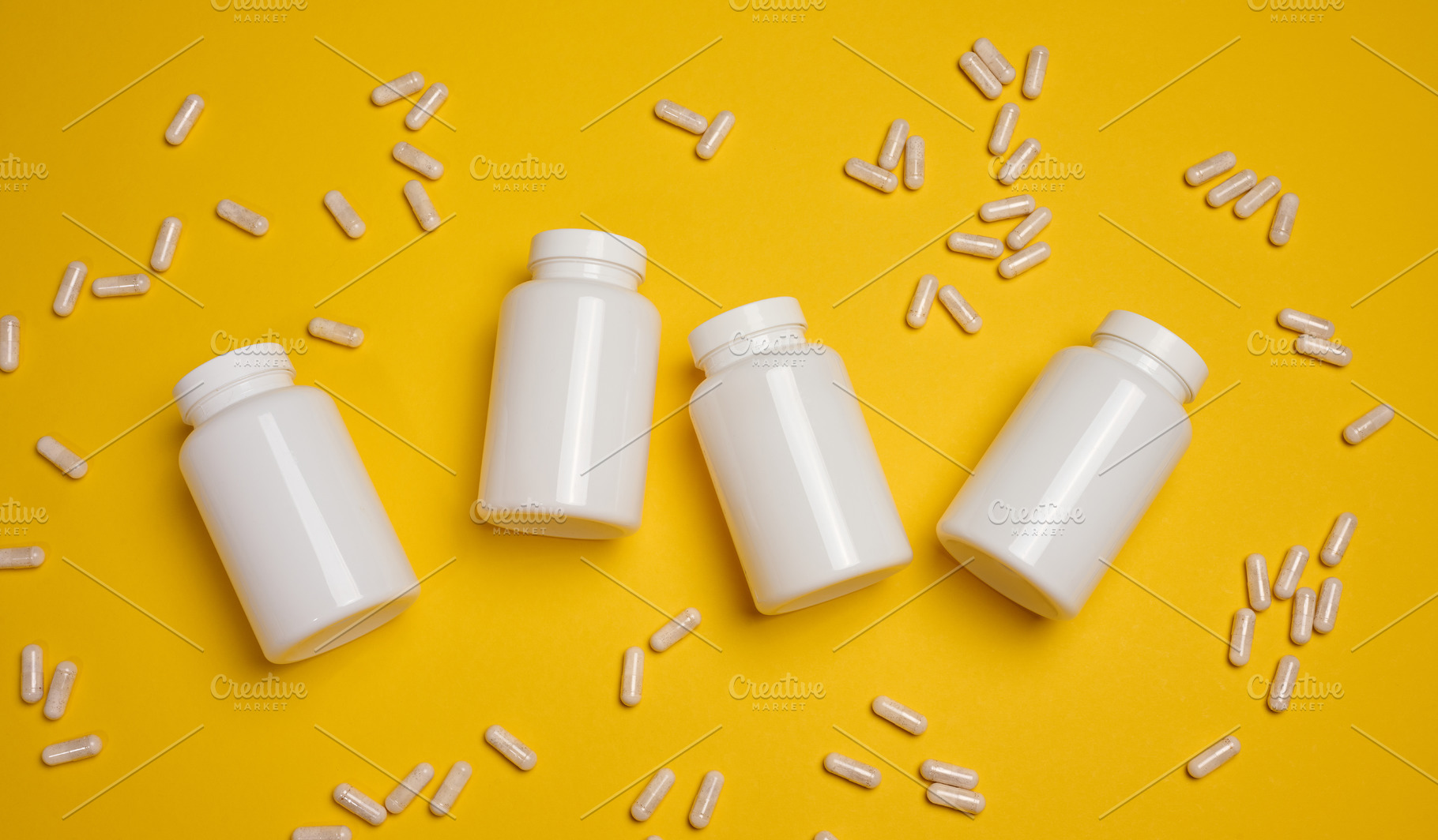 White capsules spilling from an open white plastic bottle, yello, a Health & Medical Photo by ndanko