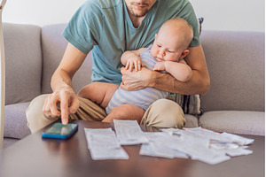 Father sitting on sofa holding baby, a Business Photo by Elizaveta Galitskaya
