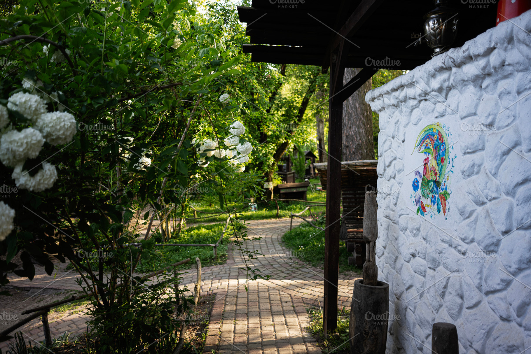 Scenic garden pathway bordered by flowers with artistic wall design in sunny li, a Photo by AS photostudio
