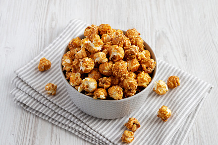 Homemade Caramel Popcorn in a gray Bowl on a white wooden backgr, a Food & Drink Photo by LiudmylaChuhunova