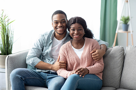 Smiling african american man and woman posing at home, a Photo by Prostock-Studio