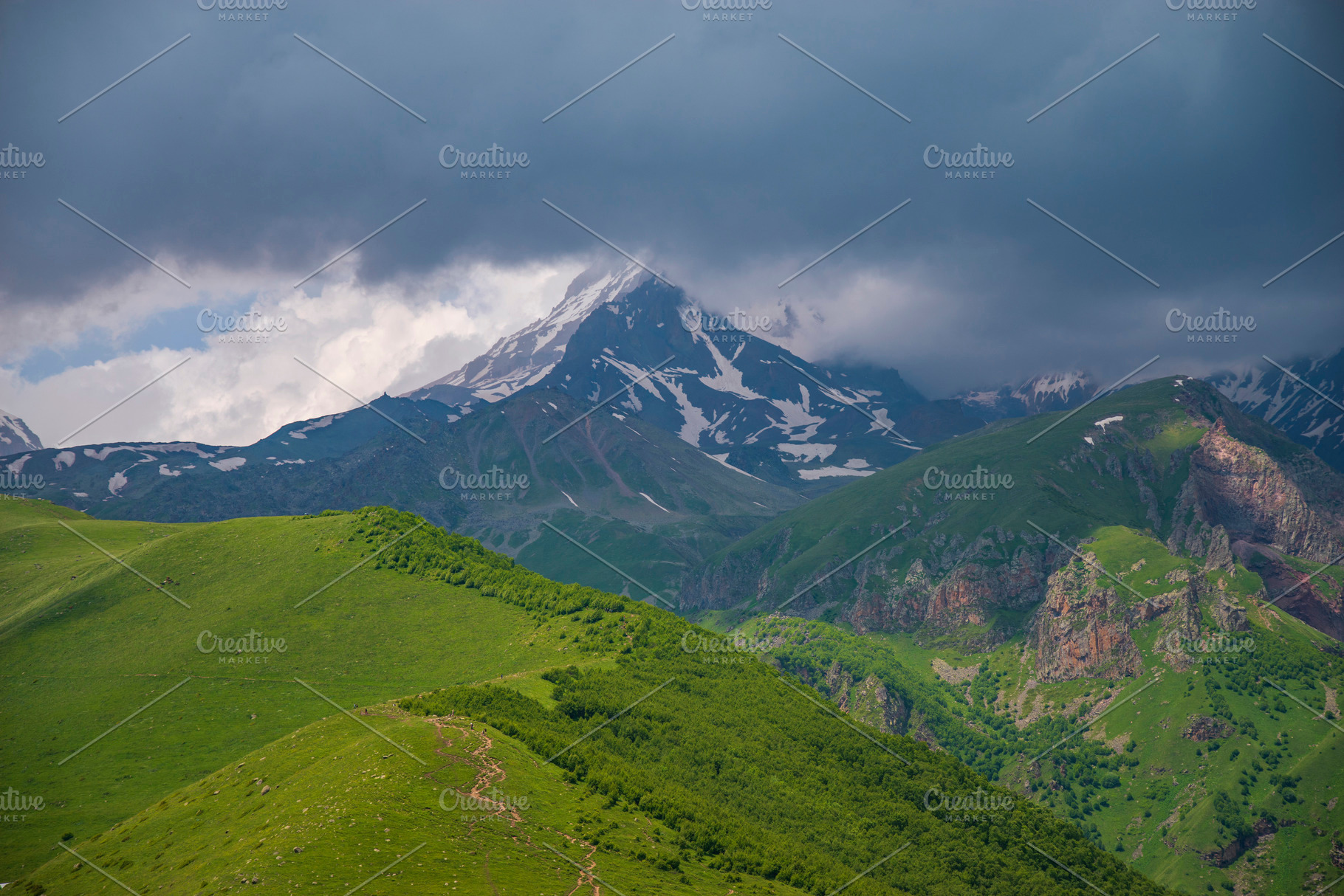 Mount Kazbek in stormy clouds above green ridges of Caucasus wit, a Photo by Pictures for you!!!!!!!!!