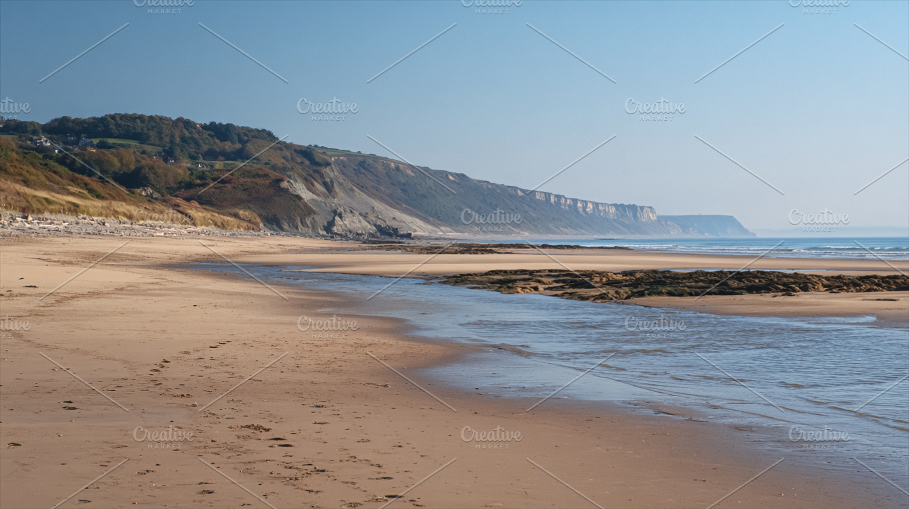 Jurassic Coast beach landscape with sandy shore, cliffs, stream,, a Photo by Studio ANNA