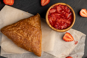 a puff pastry bun with strawberry and cherry flavor lies on paper, a Photo by rsoollAI