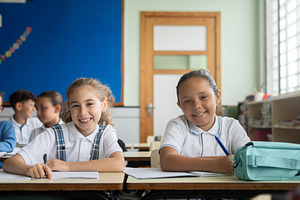 Elementary school girls smiling at the camera during a classroom lesson, a School & Education Photo by etorres69