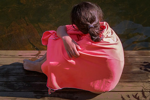 Teen woman wrapped in a blanket at border of river, a Person Photo by DanFLCreativo
