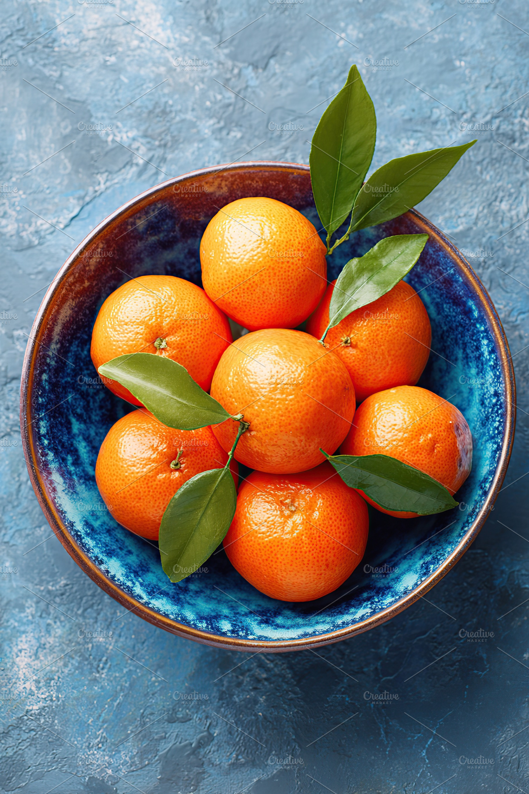 Fresh tangerines arranged in a decorative bowl with leaves, a Photo by AlyaAnd