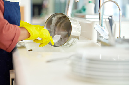 Hands of woman, gloves and washing dishes in kitchen, brush chores and house work, cleaner service and home care. Cleaning, soap and water, housekeeper working in apartment with dirt and foam at sink, a Photo by Peopleimages.com