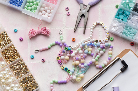 Colorful beads and jewelry making supplies arranged on pink tile, an Arts & Entertainment Photo by Olena Rudo