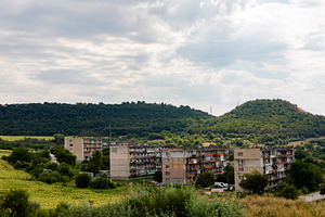 A cluster of aged apartment blocks surrounded by lush greenery and rolling hill, an Architecture Photo by Ales Munt