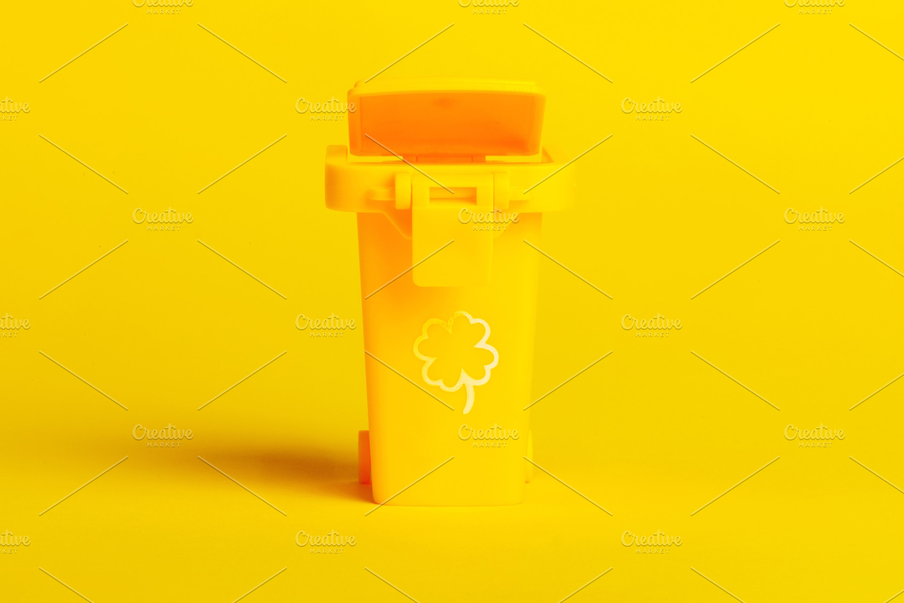 Minimalist yellow trash bin with clover icon, isolated on vibrant yellow backgr, a Technology Photo by Ales Munt