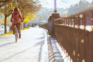 female in red rain coat outdoors in city riding bicycle, a Person Photo by Alliance Images