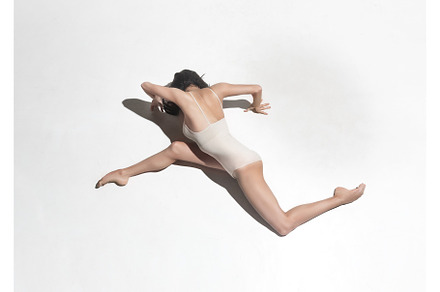 Young beautiful dancer in beige dress dancing on gray background stock photo, a Sports & Recreation Photo by Volodymyr Melnyk