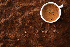 Cup of frothy coffee in corner over ground with beans, a Food & Drink Photo by Davizro's Market