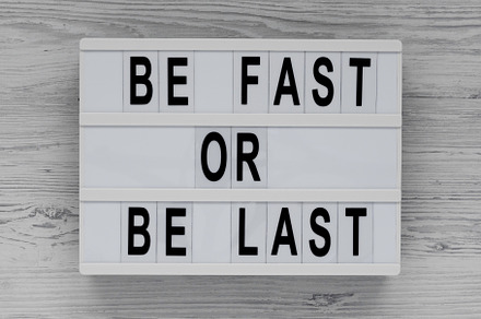 'Be Fast or Be Last' on a lightbox on a white wooden background,, a Business Photo by LiudmylaChuhunova