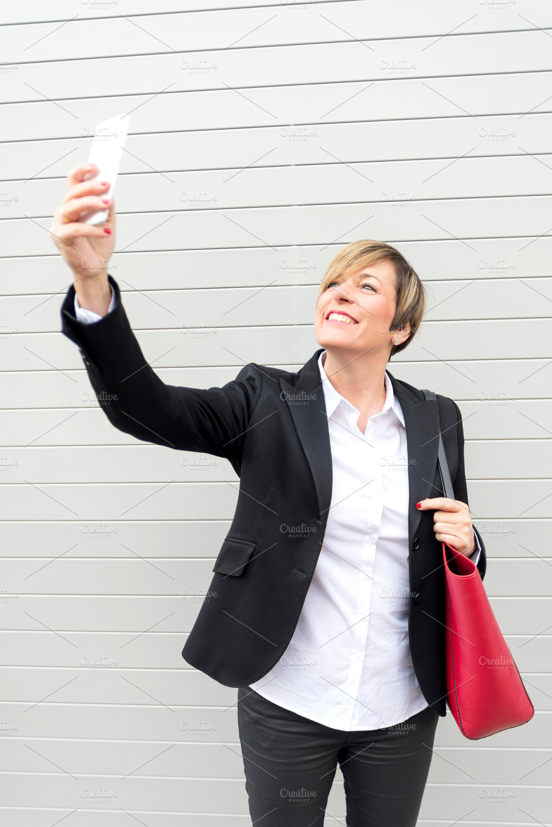 Businesswoman taking selfie with smartphone outdoors, a Photo by RF Images
