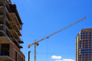 Tall yellow tower crane operating between an unfinished building, an Architecture Photo by Ales Munt