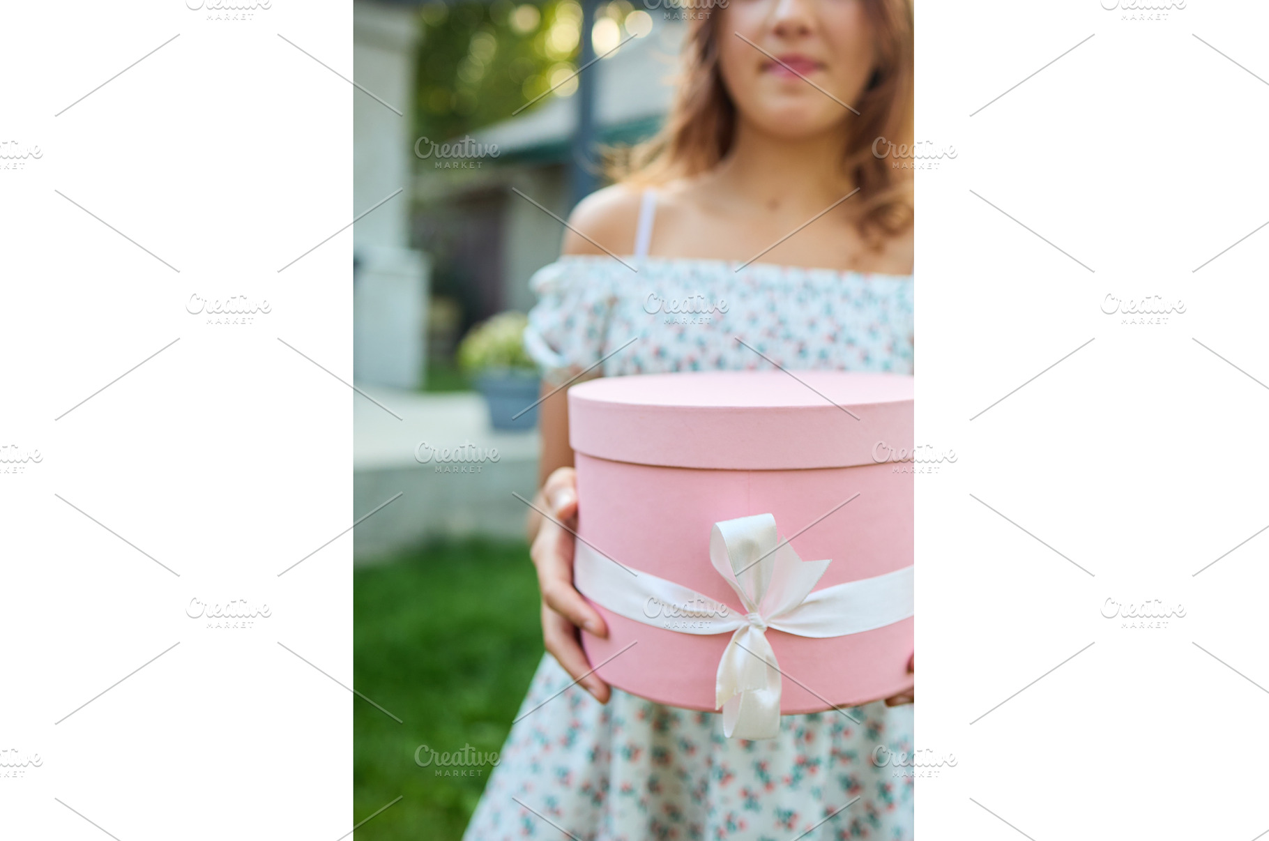 Young girl holds gift box in garden, a Nature Photo by IlliaBondarPhotography