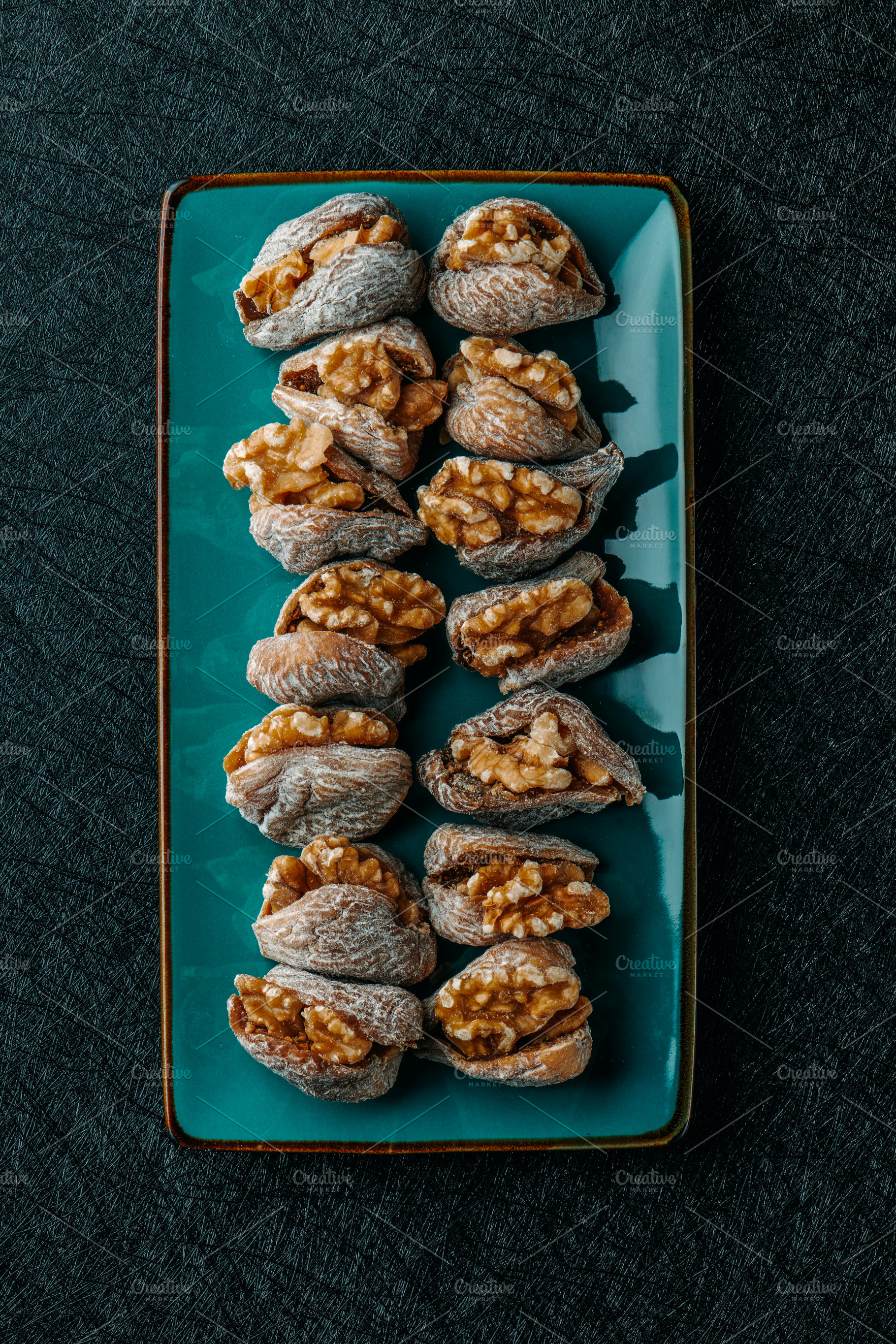 plate with some dried figs filled with walnuts, a Photo by Nito