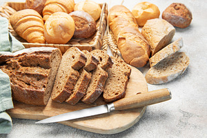 Assorted baked bread loaves and rolls on cutting board, a Food & Drink Photo by Olena Rudo