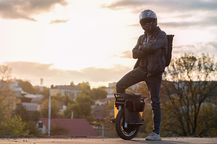 A young male rider in protective gear with a backpack on an electric unicycle a